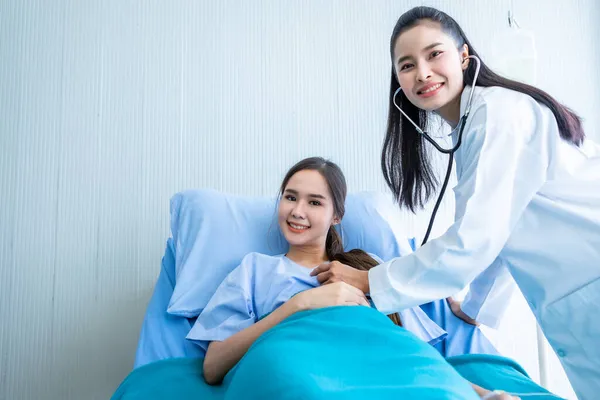 결과를 기록하기 확인하는 의사의 검사를 침대에 아시아인젊은 환자웃는 얼굴은 주변에서 — 스톡 사진