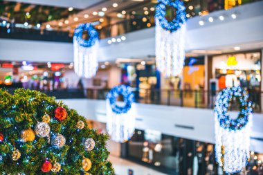 Mutlu Noel 'ler, renkli baloları, hediye kutularını ve Noel kutlaması paketlerini kapatın, alışveriş merkezinin arka planındaki yeşil Noel ağacında Noel ve yeni yıl süslemeleriyle süsleyin..
