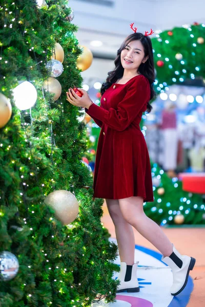 ポートレート美しい若いアジアの女性の赤いドレスの衣装とクリスマスグリーティング画像小包の装飾クリスマスツリーライト円形のボケの背景装飾クリスマスと新年の間 — ストック写真