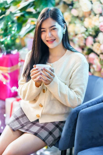 自宅のリビングルームでコーヒー ミルクやチョコレートのカップを持って正の肖像画の美しい若いアジアの女性は屋内装飾クリスマスの間にXママと新年の休日 — ストック写真