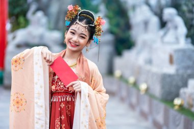 Asyalı Mutlu, antik Çin kostümleri giyen küçük güzel kız Çin Yeni Yıl Festivali için kırmızı zarflar tutuyor Çin kültürünü Tayland 'daki halka açık yerlerde kutluyor.