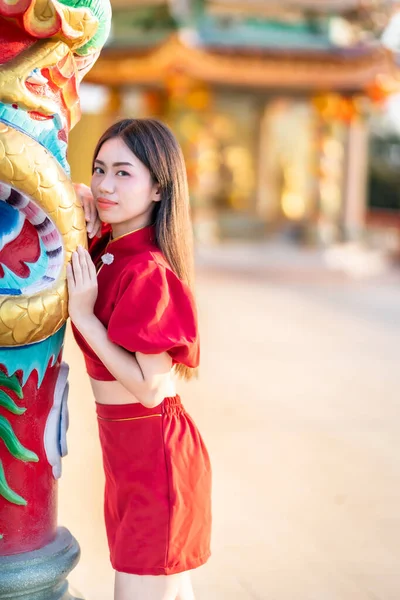 肖像画美しい笑顔アジアの若い女性は タイの中国の神社公共の場所で中国の文化を祝う中国の旧正月の祭りのための赤いChongsamドレス伝統的な装飾を身に着けている — ストック写真