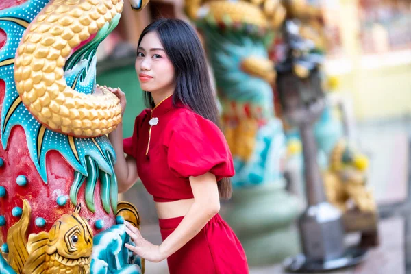 肖像画美しい笑顔アジアの若い女性は タイの中国の神社公共の場所で中国の文化を祝う中国の旧正月の祭りのための赤いChongsamドレス伝統的な装飾を身に着けている — ストック写真