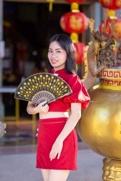 肖像画美しい笑顔アジアの若い女性は タイの中国の神社で中国の旧正月の祭りのための中国のファニングを開催し 赤い伝統的な中国のChongsam装飾を身に着けている — ストック写真