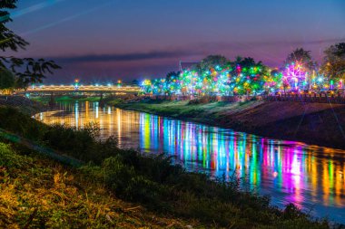 Büyük Naresuan Festivali ve Tayland 'ın Phitsanulok kentinde düzenlenen Yıllık Kızıl Haç etkinliği için Naresuan Köprüsü' ndeki köprüde gece Nan Nehri üzerinde güzel bir ışık var..