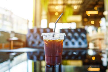 Americano buzlu kahvenin yakın çekimi ya da iş konsepti sırasında, bahçedeki kafede cam ahşap masa masasının üzerinde fincanda sade kahve.