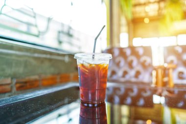 Americano buzlu kahvenin yakın çekimi ya da iş konsepti sırasında, bahçedeki kafede cam ahşap masa masasının üzerinde fincanda sade kahve.