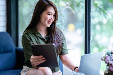 Asyalı serbest çalışanlardan memnun. Günlük iş kadınları dizüstü bilgisayarla çalışıyor ve kahve fincanı ve kahve fincanı ile tablet kullanıyor. Arka plan, iletişim kavramı gibi.