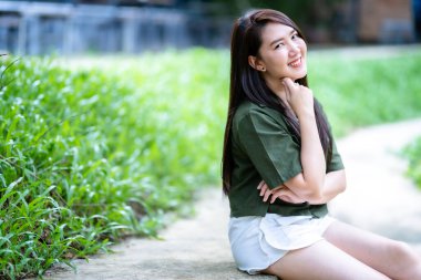 Güzel mutlu Asyalı kadın gezginin portresi kahverengimsi yeşil elbise şık hippi yaz güneşli bir hayat tarzı sokakta güneşli bir yaz günü park arka planında