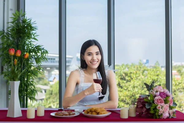 バレンタインデーのコンセプトは アジアの若い女の子はワイングラスと赤とピンクのバラのワインの花束とテーブルフードに座って レストランの背景にある彼女の男を待っています — ストック写真