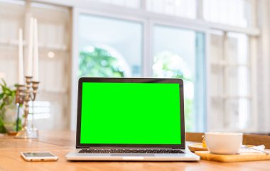 Kahve dükkanının arka planında boş ekranlı ve akıllı telefonlu dizüstü bilgisayarın bir kopyası, yeşil ekran.