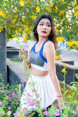 Portrait of beautiful athletic young asian woman in fashionable sportswear standing and having rest after strong exercise training in garden the park,Outdoor Sporty concept