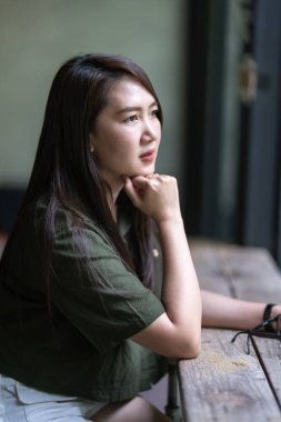 a portrait of beautiful happy asian woman traveler wearing brownish green dress stylish hipster Summer sunny lifestyle in coffee shop like the background