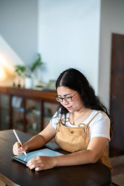 Asyalı serbest yazar, iş kadını, gözlüklü, şık hippi çizer, elektronik kalemle dijital tablete not alır, internette gezinir, sohbet eder ve kafede blog yazar..