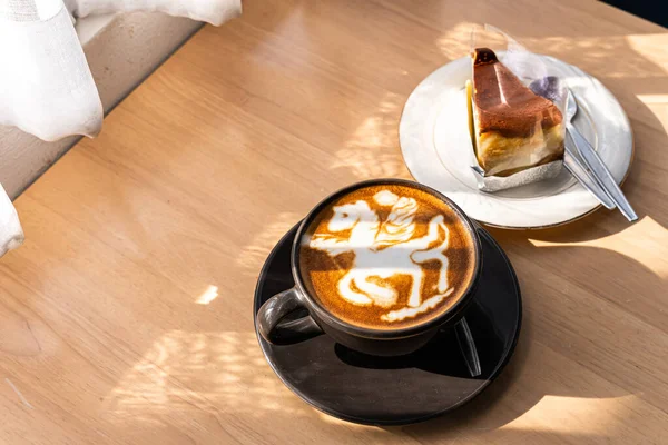 Hot coffee latte with latte art in the form of a horse milk foam in cup mug and Homemade chocolate cake on wood desk on top view. As breakfast In a coffee shop at the cafe,during business work concept