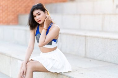 Portrait of beautiful athletic young asian woman in fashionable sportswear standing and having rest after strong exercise training in garden the park,Outdoor Sporty concept