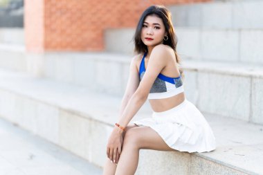Portrait of beautiful athletic young asian woman in fashionable sportswear standing and having rest after strong exercise training in garden the park,Outdoor Sporty concept