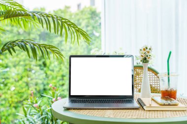 Boş ekranlı dizüstü bilgisayarın bir kopyası. Not defteri, buzlu kahve ve akıllı telefon. Kafedeki kahve dükkanının penceresinin yanında.