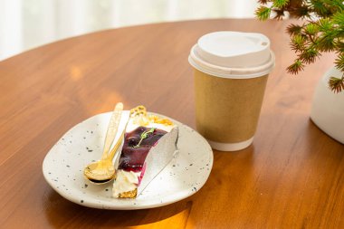 Sütlü sütlü sütlü sütlü sıcak kahve, kağıttan yapılma ve ahşap masadaki yabanmersinli kek. İş görüşmeleri sırasında kafedeki bir kafede kahvaltı olarak.