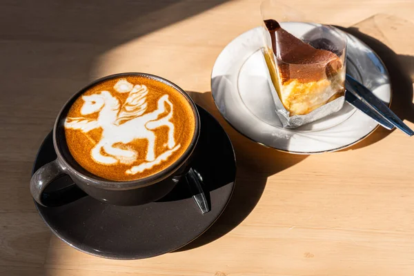 Hot coffee latte with latte art in the form of a horse milk foam in cup mug and Homemade chocolate cake on wood desk on top view. As breakfast In a coffee shop at the cafe,during business work concept