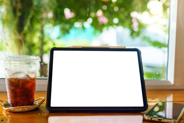 Mockup of digital tablet with empty screen with coffee and smartphone isolate on wooden office desk in coffee shop like the background ,White screen