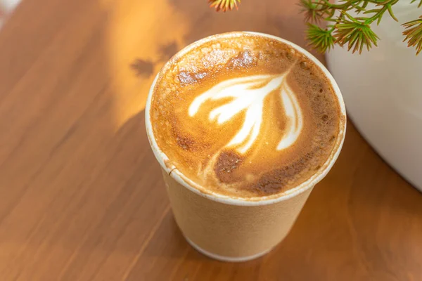 木製の机の上に紙で作られたカップの中にラテアートミルクフォームとホットコーヒーラテ 朝食としてカフェのコーヒーショップでは ビジネスワークコンセプト中 — ストック写真
