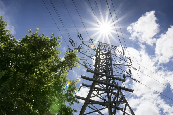 Linee ad alta tensione e sole luminoso illustrano le esigenze di potenza estiva — Foto Stock