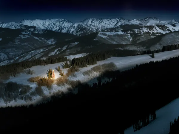 Árbol de Navidad Brightly Lit Mountain brilla mágicamente en la nieve por la noche Fotos de stock