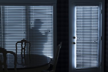 Silhouette of Burglar Sneeking Up To Backdoor At Night clipart