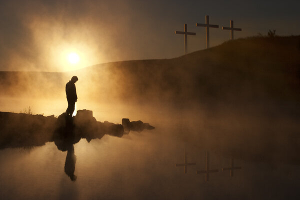 Утреннее солнце и туман окружают силуэт туриста на спокойном озере
