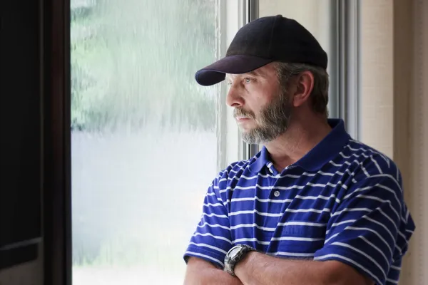 Homme adulte se demande avenir regardant dehors fenêtre couverte de pluie — Photo