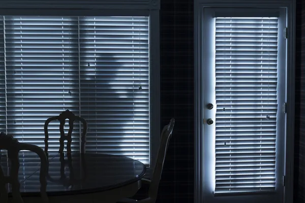 Silueta de ladrón escabulléndose hasta puerta trasera en la noche — Foto de Stock