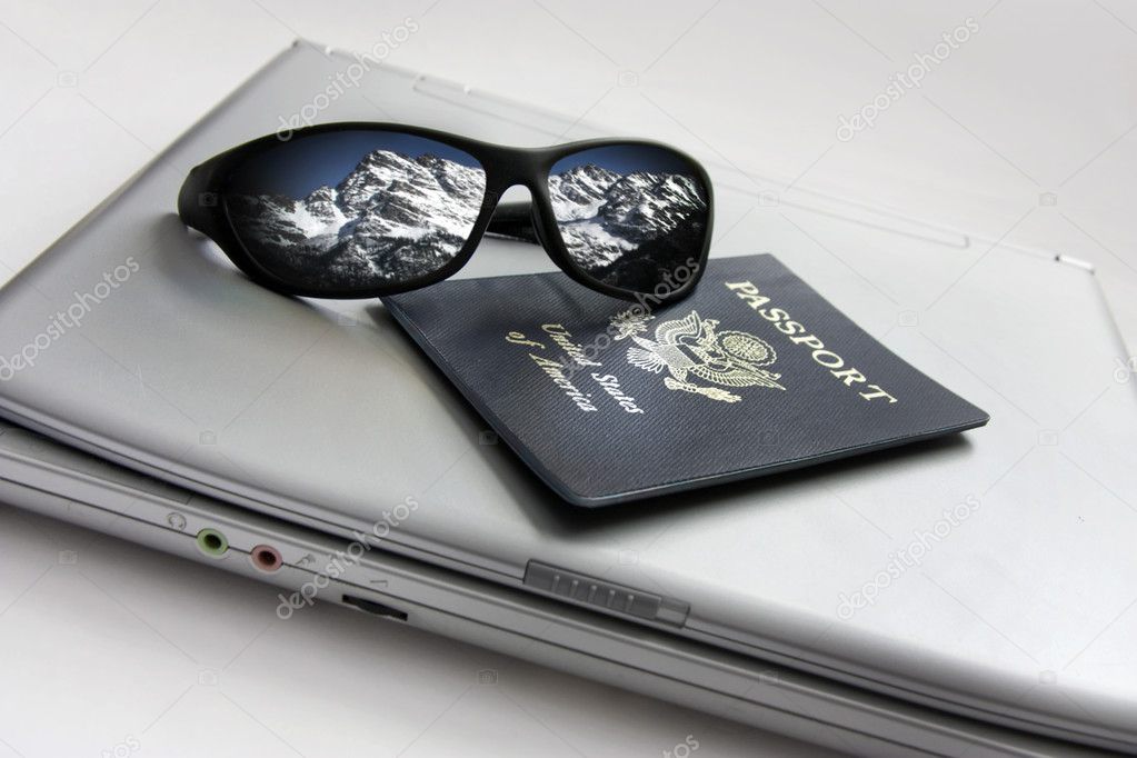 Sunglasses reflecting the snowy mountains with international passport and compact laptop