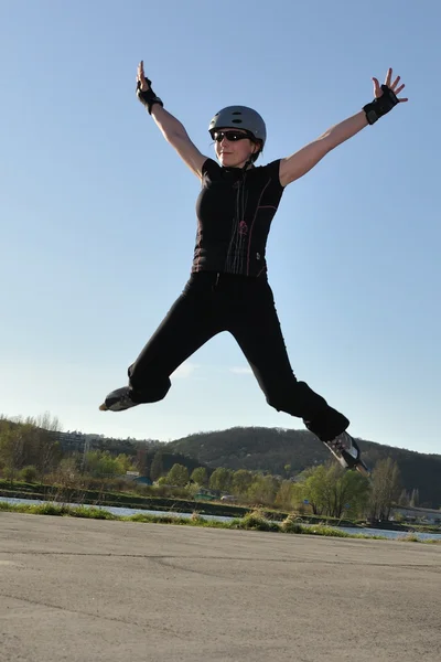 Femme saute sur patins à roues alignées — Photo