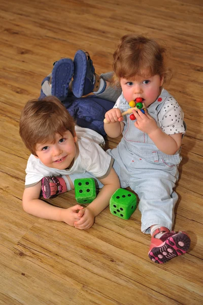 Gelukkig broer en zus op houten vloer met speelgoed — Stockfoto