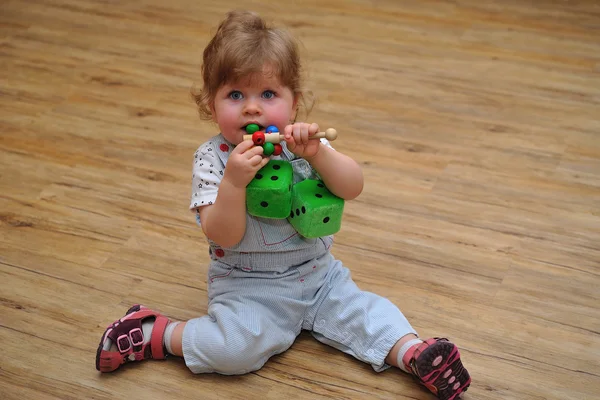 Menina pequena sentada no chão de madeira e brincar com brinquedos — Fotografia de Stock