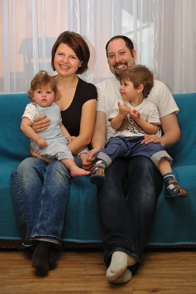 Familia feliz sentada en un sofá azul —  Fotos de Stock