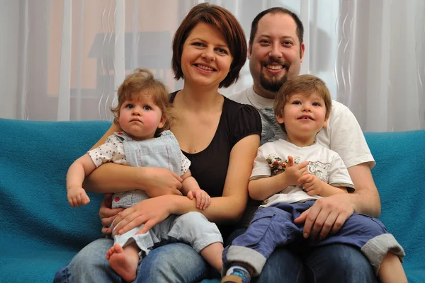 Familia feliz sentada en un sofá azul —  Fotos de Stock