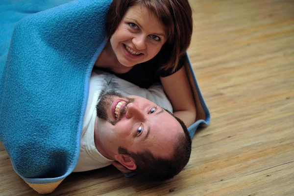 Casal feliz envolto em cobertor azul — Fotografia de Stock