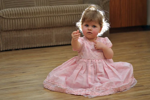 Niña en vestido rosa couriosly mirando su mano — Foto de Stock