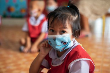 CHIANG MAI, THAILAND - 23 Mart 2021: Taylandlı çocuklar Chiang Mai, Tayland 'daki anaokulunda toz ve mikropları önlemek için maske takıyorlar.