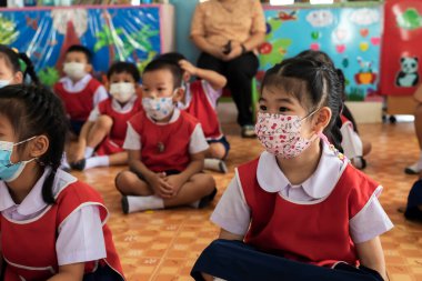 CHIANG MAI, THAILAND - 23 Mart 2021: Taylandlı çocuklar Chiang Mai, Tayland 'daki anaokulunda toz ve mikropları önlemek için maske takıyorlar.