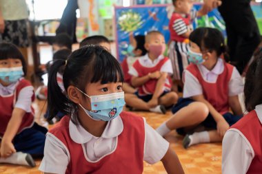 CHIANG MAI, THAILAND - 23 Mart 2021: Taylandlı çocuklar Chiang Mai, Tayland 'daki anaokulunda toz ve mikropları önlemek için maske takıyorlar.