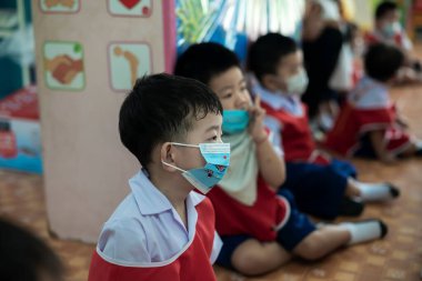 CHIANG MAI, THAILAND - 23 Mart 2021: Taylandlı çocuklar Chiang Mai, Tayland 'daki anaokulunda toz ve mikropları önlemek için maske takıyorlar.