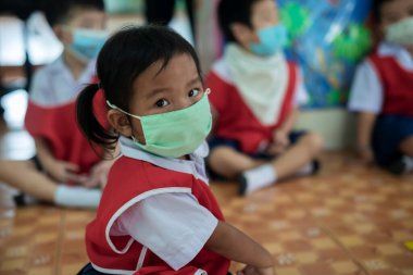 CHIANG MAI, THAILAND - 23 Mart 2021: Taylandlı çocuklar Chiang Mai, Tayland 'daki anaokulunda toz ve mikropları önlemek için maske takıyorlar.