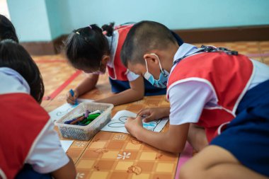 CHIANG MAI, THAILAND - 23 Mart 2021: Taylandlı çocuklar anaokulunda kağıt üzerinde mum boyamakla eğleniyorlar. Chiang Mai, Tayland 'da