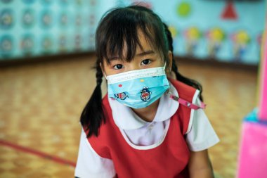 CHIANG MAI, THAILAND - 23 Mart 2021: Taylandlı çocuklar Chiang Mai, Tayland 'daki anaokulunda toz ve mikropları önlemek için maske takıyorlar.
