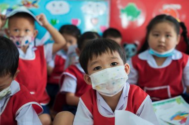 CHIANG MAI, THAILAND - 23 Mart 2021: Taylandlı çocuklar Chiang Mai, Tayland 'daki anaokulunda toz ve mikropları önlemek için maske takıyorlar.