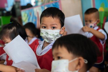 CHIANG MAI, THAILAND - 23 Mart 2021: Taylandlı çocuklar Chiang Mai, Tayland 'daki anaokulunda toz ve mikropları önlemek için maske takıyorlar.