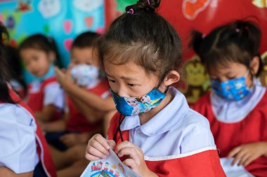 CHIANG MAI, THAILAND - 23 Mart 2021: Asyalı Taylandlı çocuklar ve onların mum boyaları bir anaokulunda kağıt üzerinde çalışırlar. Chiang Mai, Tayland 'da